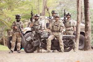 Portrait of soldiers in camouflage uniforms hold weapons in front of a military communication vehicle photo