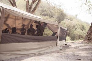 Group of soldiers in camouflage uniforms hold weapons in a field tent, Plan and prepare for combat training. photo