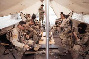 Group of soldiers in camouflage uniforms hold weapons in a field tent, Plan and prepare for combat training. photo