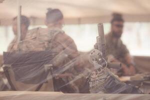 Group of soldiers in camouflage uniforms hold weapons in a field tent, Plan and prepare for combat training. photo