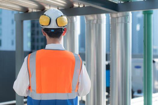 Back view of Engineers inspect the completed air conditioning and water systems to continue verifying their functionality. photo
