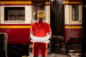 Portrait of railway technician worker in safety vest and helmet working with blueprint at train repair station photo