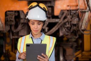 Portrait of railway technician worker in safety vest and helmet working with blueprint at train repair station photo