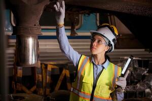 Portrait of railway technician worker in safety vest and helmet working with blueprint at train repair station photo