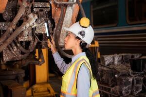 Portrait of railway technician worker in safety vest and helmet working with blueprint at train repair station photo