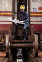 Railway technician in uniform and helmet inspect the train wheels removed from the locomotives in the train workshop. photo
