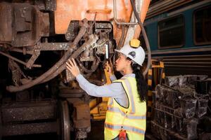 Portrait of railway technician worker in safety vest and helmet working with blueprint at train repair station photo