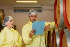 Mature female and male researchers and developers working in winery, Testing wine that has been fermented for a while. photo
