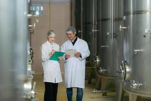 Mature female and male researchers and developers working in winery, Testing wine that has been fermented for a while. photo