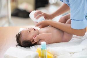 Following a bath, a mother applies powder and dresses her tiny daughter. photo