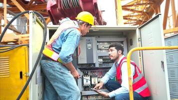 Bothe of electrical engineer inspects the electrical control board of a crane before putting it to use on a construction site photo