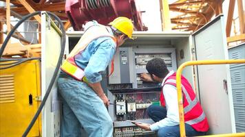 Bothe of electrical engineer inspects the electrical control board of a crane before putting it to use on a construction site photo