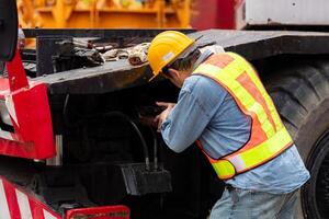 Engineers and technicians grease the wheel axle of a large crane before moving to the construction site photo