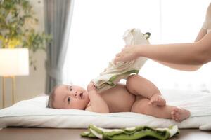 A tiny child smiles happily on the bed waiting for mother apply powder and put on clothes after taking a bath photo