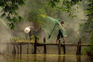 The farmer helps and talks to the fisherman who is using a fishnet to catch fish in the river photo