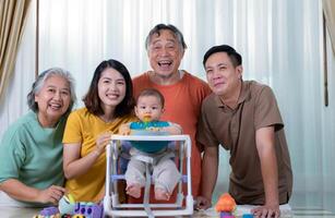 un pequeño niño comiendo su primero comida, padres y abuelos animar emocionado foto