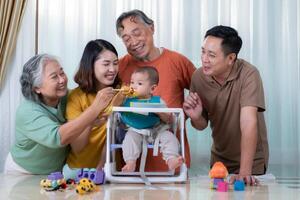 un pequeño niño comiendo su primero comida, padres y abuelos animar emocionado foto