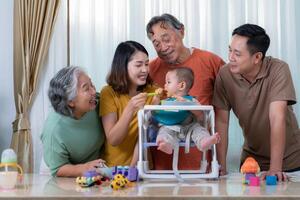 un pequeño niño comiendo su primero comida, padres y abuelos animar emocionado foto