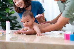 A tiny child happily on the towel waiting for parents apply powder and put on clothes after taking a bath photo