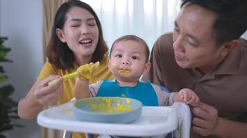 un pequeño niño comiendo su primero comida, padres animar emocionado foto