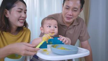 un pequeño niño comiendo su primero comida, padres animar emocionado foto