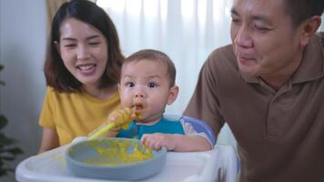 un pequeño niño comiendo su primero comida, padres animar emocionado foto