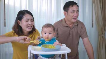 un pequeño niño comiendo su primero comida, padres animar emocionado foto
