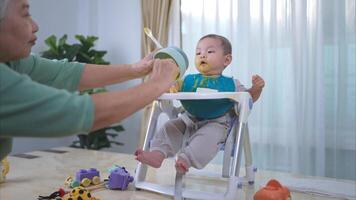 un pequeño niño comiendo su primero comida, madre y abuela animar emocionado foto
