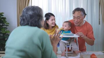 un pequeño niño comiendo su primero comida, padres y abuelos animar emocionado foto