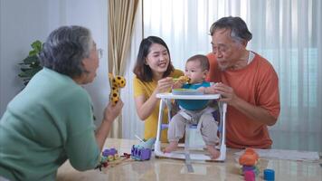 un pequeño niño comiendo su primero comida, padres y abuelos animar emocionado foto