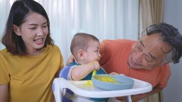 un pequeño niño comiendo su primero comida, madre y abuelo animar emocionado foto