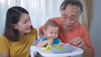 un pequeño niño comiendo su primero comida, madre y abuelo animar emocionado foto