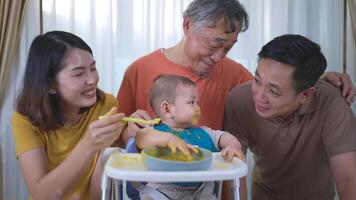 un pequeño niño comiendo su primero comida, padres y abuelo animar emocionado foto