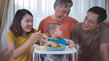 un pequeño niño comiendo su primero comida, padres y abuelo animar emocionado foto