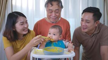 un pequeño niño comiendo su primero comida, padres y abuelo animar emocionado foto