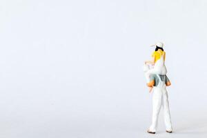 Miniature scene depicting a father carrying his daughter on his shoulders on white background photo