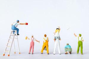 Miniature figures dressed as painters in overalls on a clean white background photo