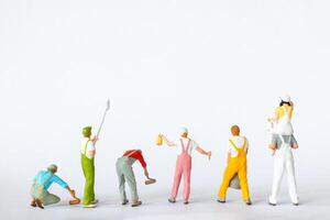 Miniature figures dressed as painters in overalls on a clean white background photo