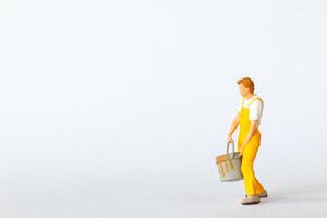 Miniature figure of a painter dressed in yellow overalls on white background photo