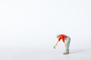 Miniature figure of a painter in a red shirt leaning forward as if painting with a brush on a white background photo
