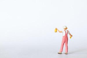 Miniature figure dressed in pink overalls and a white cap on a clean white background photo