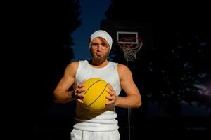Man holding a basketball in a park at dusk, showcasing athleticism and confidence by the court photo