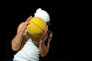 A basketball player in a white outfit poses confidently with a yellow ball in night park photo