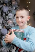 Boy holding christmas gift in front of decorated tree photo