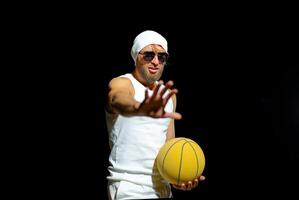 A basketball player in a white outfit poses confidently with a yellow ball in night park photo