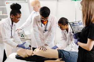 Group of people learning how to make first aid heart compressions with dummies during the training photo