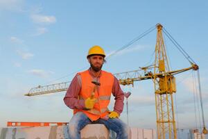 Construction worker sitting and holding hammer at construction site photo