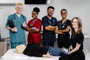 Group of doctors standing at the bed with mannequin at first aid training course photo