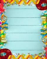 A colorful border with ribbons and confetti on a wooden background photo