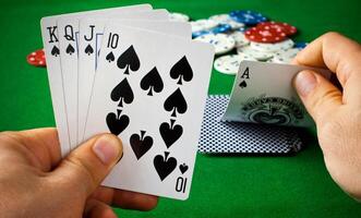 A person holding four cards in front of a green table photo